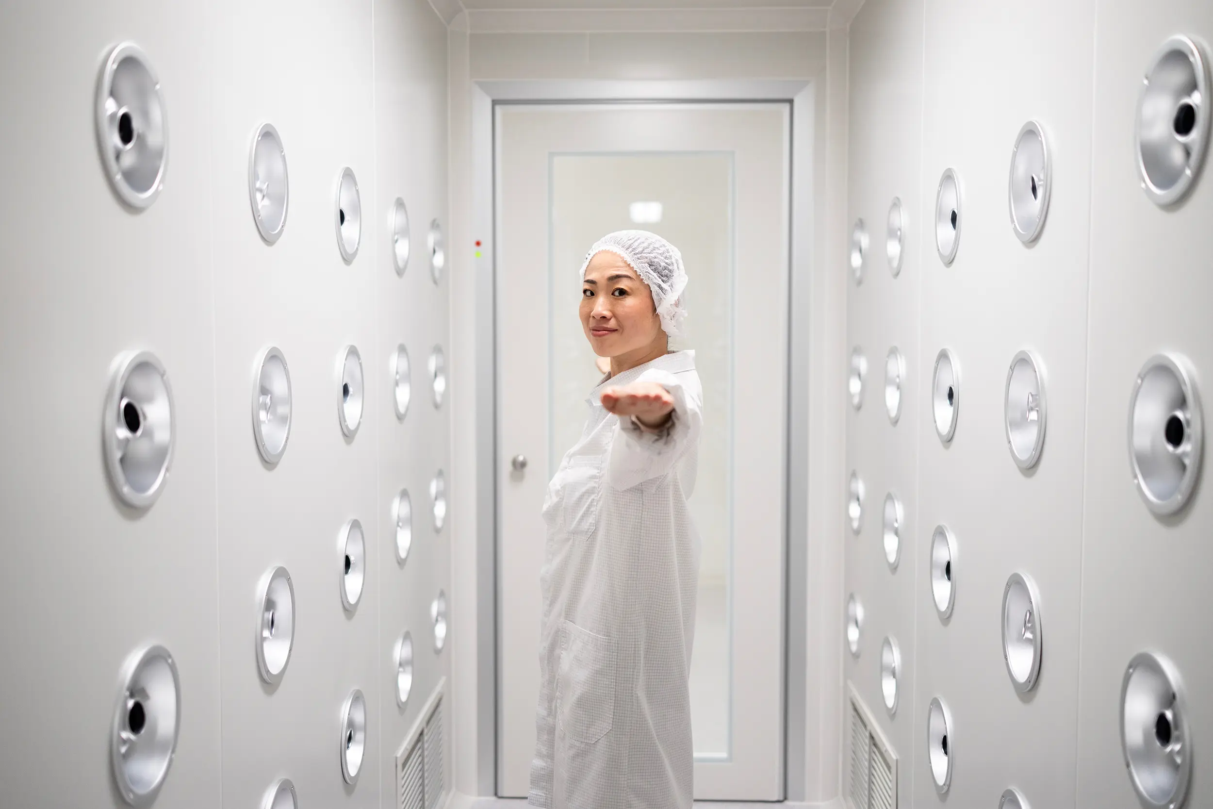 A photography of a cleanroom gowned woman in a high air pressure airlock.